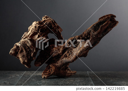 Old dry wooden snag on a black stone table. Old dry wooden snag on a black stone table. 142219885