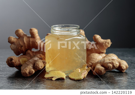 Ginger jam in jar and fresh ginger roots on a black background. Ginger jam in jar and fresh ginger roots on a black background. 142220119