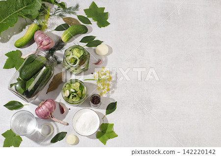 Cucumbers with dill, garlic, horseradish, pickling leaves, and pickled cucumbers in jars on the kitchen counter. Harvest concept. Recipe and ingredients for homemade pickles. Concept of home canning Cucumbers with dill, garlic, horseradish, pickling leaves, and pickled cucumbers in jars on the kitchen counter. Harvest concept. Recipe and ingredients for homemade pickles. Concept of home canning 142220142
