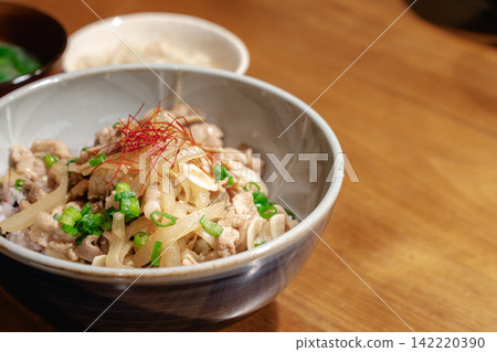 A freshly made pork bowl, still steaming, served on a wooden table. A freshly made pork bowl, still steaming, served on a wooden table. 142220390