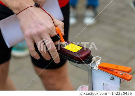 Close-up of a hand gripping an orange control lever on a mechanical device Close-up of a hand gripping an orange control lever on a mechanical device 142220439