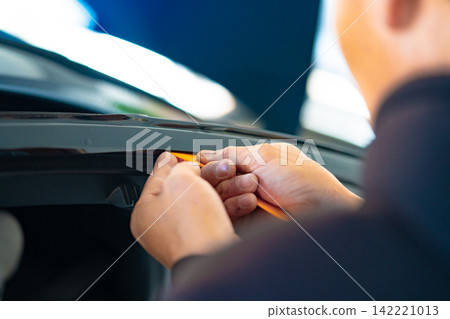 A car wrapping specialist applies a polyurethane film to the car. Detailer PPF 142221013