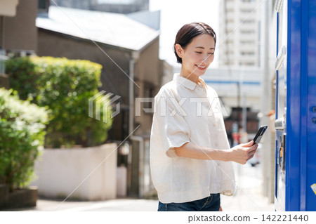 一位女士正在自動販賣機購買飲料。 一位女士正在自動販賣機購買飲料。 142221440