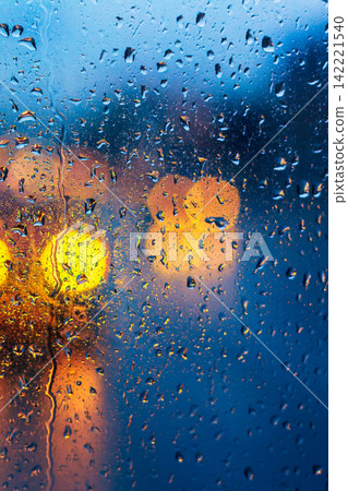 Raindrops on window with vibrant blurred yellow and blue lights 142221540
