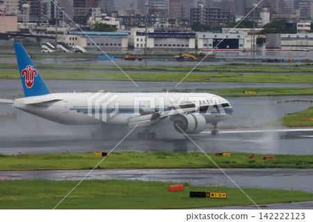 A passenger plane lands on a rainy runway, producing a plume of water from the engine's reverse thrust. A passenger plane lands on a rainy runway, producing a plume of water from the engine's reverse thrust. 142222123
