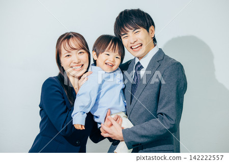 一位兩歲男孩被他上班的父母抱著。 142222557