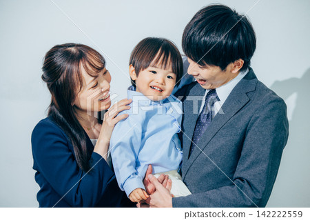 一位兩歲男孩被他上班的父母抱著。 142222559