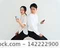 一男一女背對背操作智慧型手機。 142222900