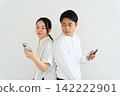 一男一女背對背操作智慧型手機。 142222901