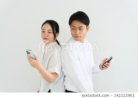 A man and a woman operating smartphones back to back. A man and a woman operating smartphones back to back. 142222901
