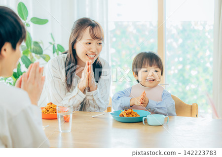一家三口正在享用義大利麵午餐。 142223783