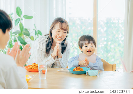一家三口正在享用義大利麵午餐。 142223784
