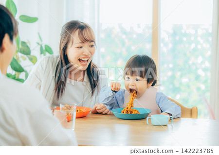 一家三口正在享用義大利麵午餐。 142223785