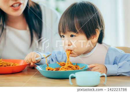 一家三口正在享用義大利麵午餐。 142223786