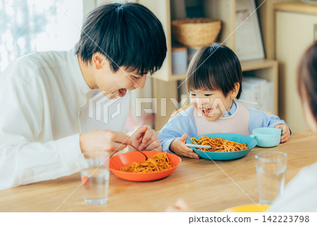 一家三口正在享用義大利麵午餐。 142223798