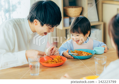 一家三口正在享用義大利麵午餐。 142223799