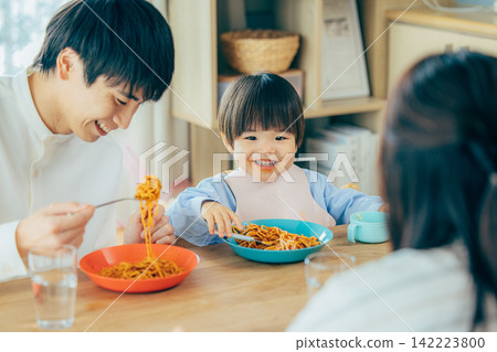 一家三口正在享用義大利麵午餐。 142223800