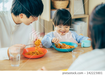 一家三口正在享用義大利麵午餐。 142223801