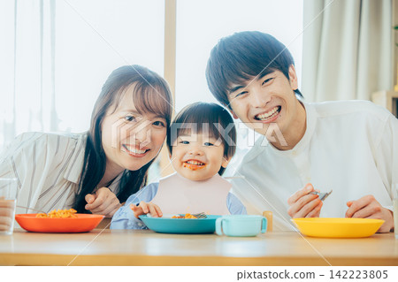 一家三口正在享用義大利麵午餐。 142223805