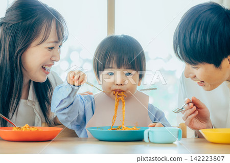 一家三口正在享用義大利麵午餐。 142223807