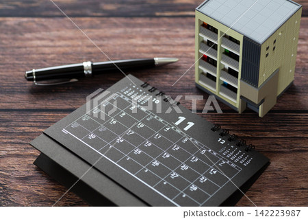 一本十一月的黑色日曆和一個公寓大樓模型。 一本十一月的黑色日曆和一個公寓大樓模型。 142223987
