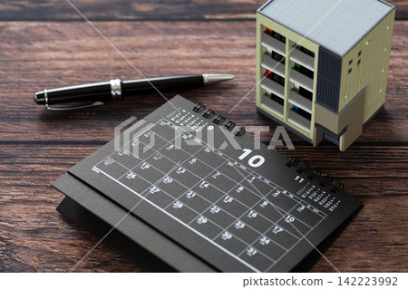一本十月份的黑色日曆和一個公寓模型大樓。 一本十月份的黑色日曆和一個公寓模型大樓。 142223992