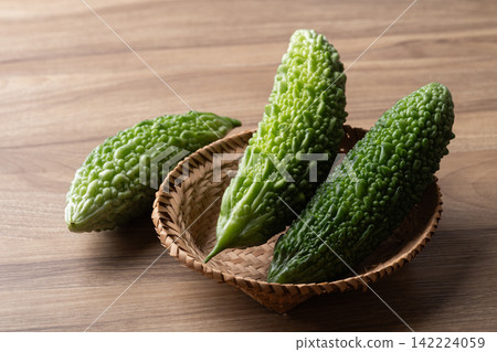 Fresh bitter gourd or bitter melon in a basket on a wooden background Fresh bitter gourd or bitter melon in a basket on a wooden background 142224059