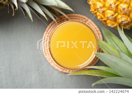 Pineapple juice in a glass with fresh pineapple on green cotton fabric background Pineapple juice in a glass with fresh pineapple on green cotton fabric background 142224074