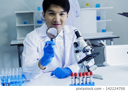 Scientist man look into Microscope research in science laboratory. Asian scientist look at microbiology microscope laboratory equipment chemistry lab. Biochemistry research experiment vaccine concept Scientist man look into Microscope research in science laboratory. Asian scientist look at microbiology microscope laboratory equipment chemistry lab. Biochemistry research experiment vaccine concept 142224708