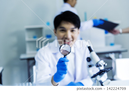 Scientist man look into Microscope research in science laboratory. Asian scientist look at microbiology microscope laboratory equipment chemistry lab. Biochemistry research experiment vaccine concept Scientist man look into Microscope research in science laboratory. Asian scientist look at microbiology microscope laboratory equipment chemistry lab. Biochemistry research experiment vaccine concept 142224709
