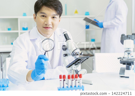 Scientist man look into Microscope research in science laboratory. Asian scientist look at microbiology microscope laboratory equipment chemistry lab. Biochemistry research experiment vaccine concept Scientist man look into Microscope research in science laboratory. Asian scientist look at microbiology microscope laboratory equipment chemistry lab. Biochemistry research experiment vaccine concept 142224711