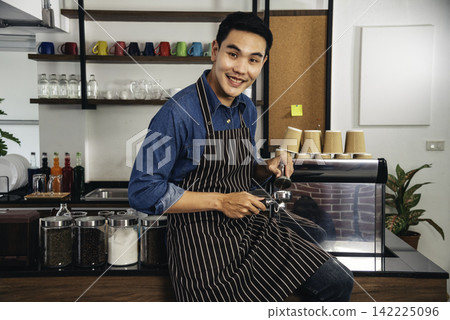 Portrait Barista small business Owner. Asian barista man coffee shop owner smiling look at camera small business confident person Entrepreneur manager professional men standing coffee counter bar Portrait Barista small business Owner. Asian barista man coffee shop owner smiling look at camera small business confident person Entrepreneur manager professional men standing coffee counter bar 142225096