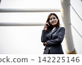 Portrait Businesswoman arms crossed smiling look at camera in modern city background. Happy Business people positive achievement standing and smile. Happy leader executive young asian women leader 142225146