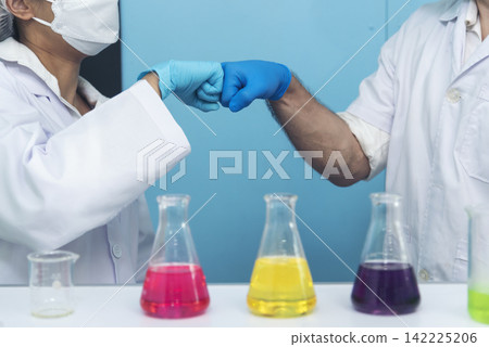 Two caucasian scientist men woman fist bump team partner shake hands together. Teamwork two scientist science chemistry research in laboratory. Close up hands pharmaceutical science team partnership Two caucasian scientist men woman fist bump team partner shake hands together. Teamwork two scientist science chemistry research in laboratory. Close up hands pharmaceutical science team partnership 142225206
