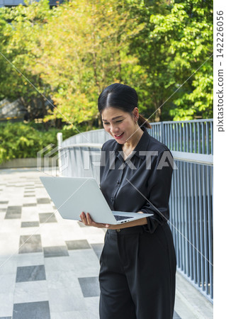 Business woman with computer laptop working outside in the park. Female professional businesswoman working outdoors. 142226056