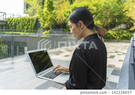 Business woman with computer laptop working outside in the park. Female professional businesswoman working outdoors. Business woman with computer laptop working outside in the park. Female professional businesswoman working outdoors. 142226057