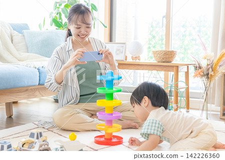 媽媽在幫孩子拍照,孩子在玩玩具 媽媽在幫孩子拍照,孩子在玩玩具 142226360