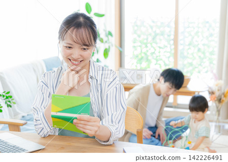 一位女士看著她的存摺，臉上帶著微笑。 142226491