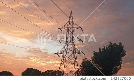 Industrial Silhouette of Power Tower and Tree Under Colorful Sunset Sky Industrial Silhouette of Power Tower and Tree Under Colorful Sunset Sky 142227060