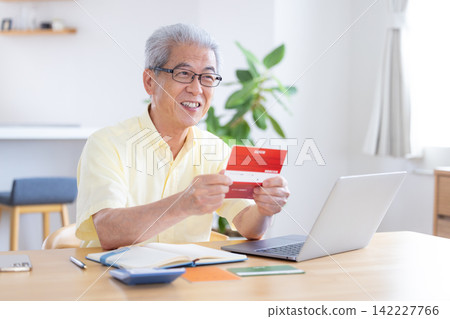 一位老人在客廳看著他的銀行存摺。 142227766
