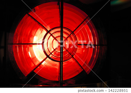 A close-up shot of the red rotating light lens of a lighthouse. 142228931
