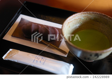 抹茶綠茶和兩份日式點心，配上黑色牙籤－來自傳統日式點心店的甜點。 142228989
