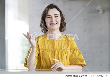 一位年輕的外國女子一邊說話一邊做手勢，並直視鏡頭。 142229294