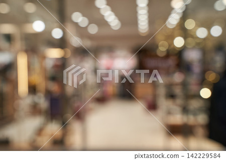 Blurred Retail Store Interior With Overhead Lights Aisles Indistinct Merchandise And Soft Bokeh Blurred Retail Store Interior With Overhead Lights Aisles Indistinct Merchandise And Soft Bokeh 142229584