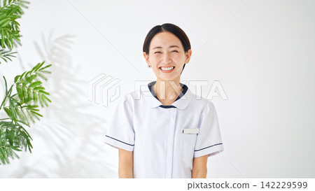 A smiling woman in a white coat. Nurse, caregiver, hospital, clinic, happy, joyful, energetic, medical office worker, receptionist, qualifications A smiling woman in a white coat. Nurse, caregiver, hospital, clinic, happy, joyful, energetic, medical office worker, receptionist, qualifications 142229599