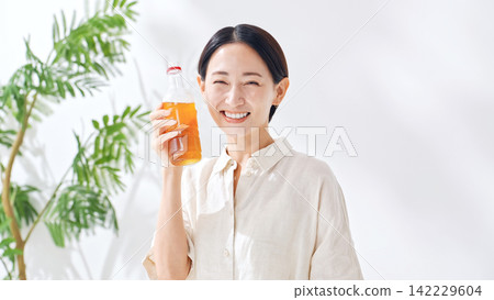 一位女士正在喝瓶裝茶。補水、烏龍茶、綠茶、紅茶、大麥茶、補水、飲料、果汁 一位女士正在喝瓶裝茶。補水、烏龍茶、綠茶、紅茶、大麥茶、補水、飲料、果汁 142229604