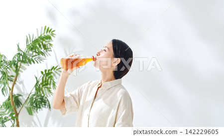 一位女士正在喝瓶裝茶。補水、烏龍茶、綠茶、紅茶、大麥茶、補水、飲料、果汁 142229605