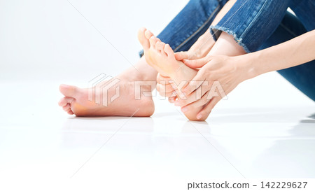 A woman massaging the soles of feet. Foot care, plantar fasciitis, stretching, rheumatism, bunions, flat feet, arches, pain. A woman massaging the soles of feet. Foot care, plantar fasciitis, stretching, rheumatism, bunions, flat feet, arches, pain. 142229627