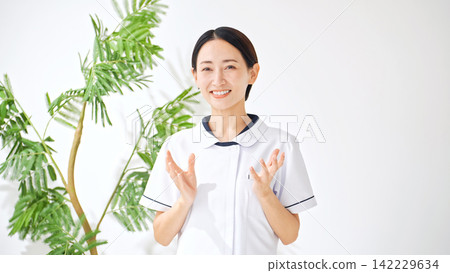 A woman in a white coat talking. Nurse, caregiver, interview, examination, medical treatment, consultation, interview, medical history taking, reporting, explanation, medical office work. A woman in a white coat talking. Nurse, caregiver, interview, examination, medical treatment, consultation, interview, medical history taking, reporting, explanation, medical office work. 142229634