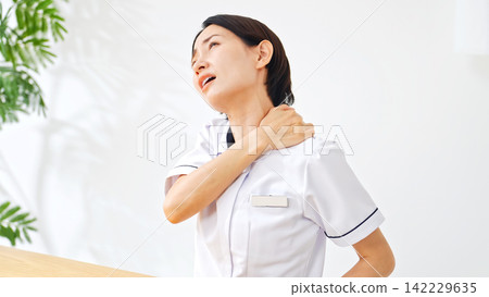 一位身穿白大褂的女士正在按摩肩膀。護士、護理員、疲憊、疲倦、肩膀僵硬、過度勞累、美容護理、精疲力竭、壓力、工作變動、醫院 142229635